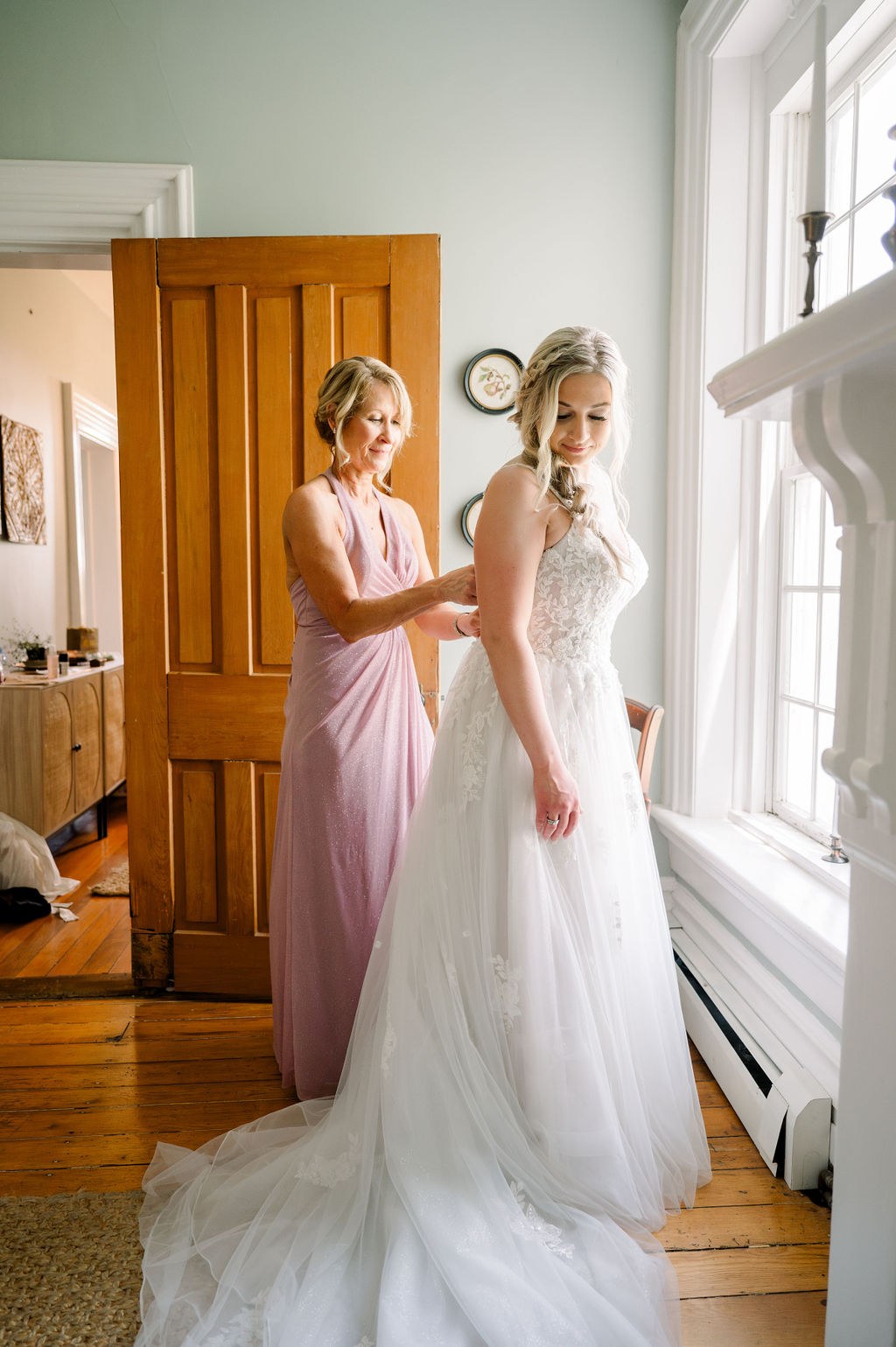 Bride getting ready by the window in the farmhouse bridal suite