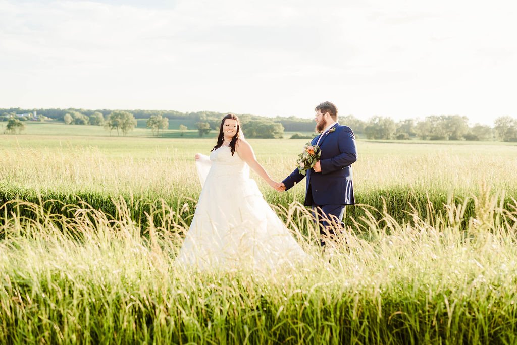 A couple in the tall grass in golden evening light.