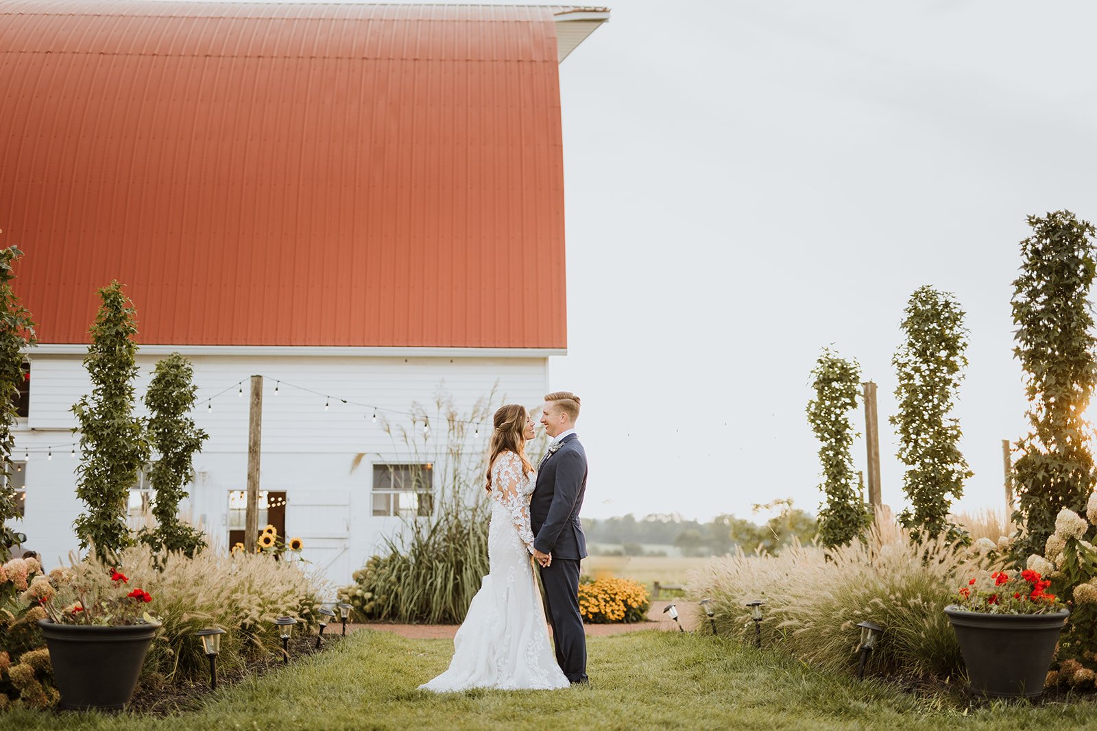 A couple outside the white barn at Wren Farm.