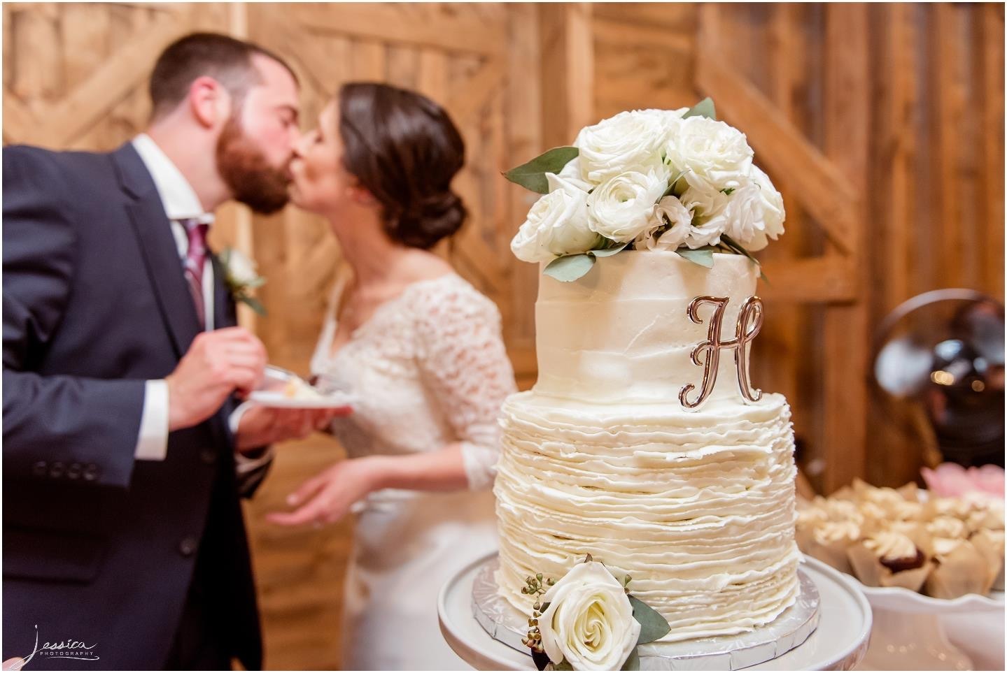A couple cutting their wedding cake inside the barn.