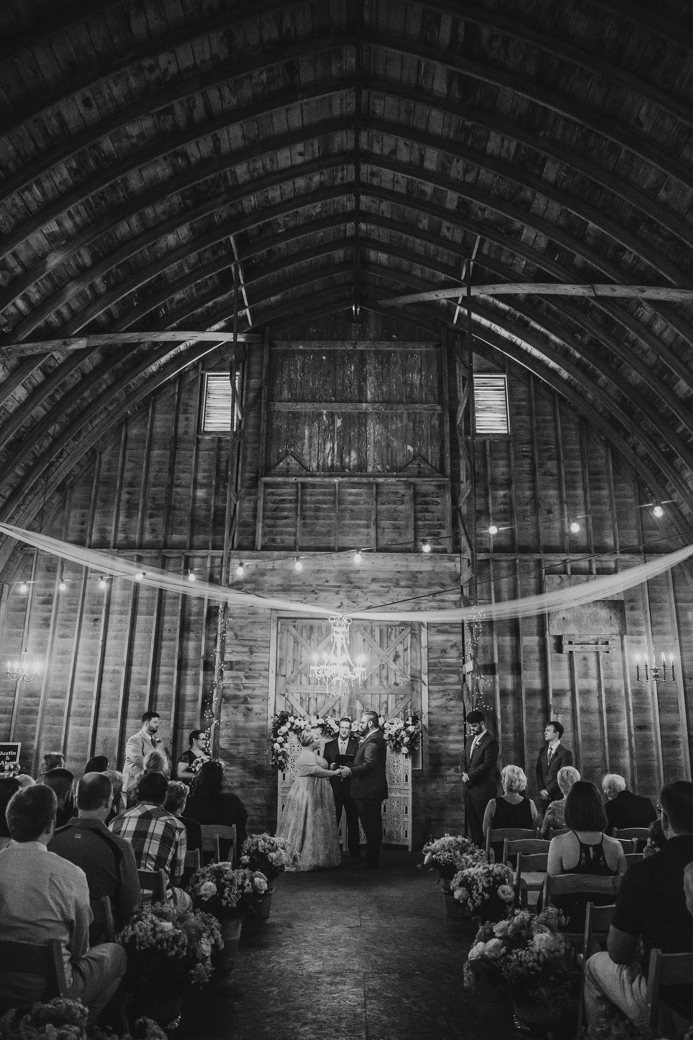 A ceremony under the barn's arched roof, in black and white.