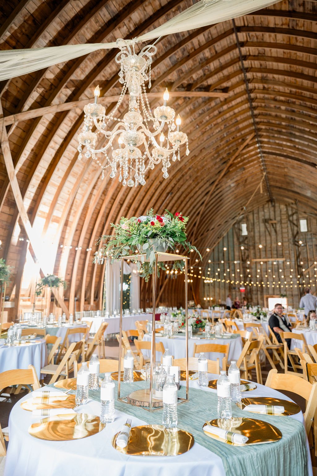 The barn interior set for a reception beneath a crystal chandelier.
