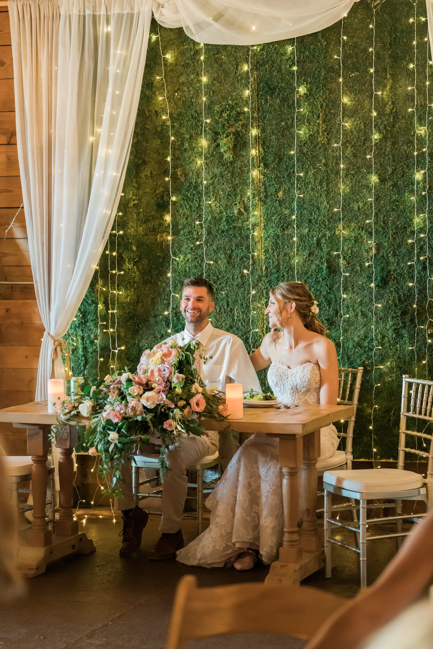 The newlyweds at their sweetheart table under the lights.