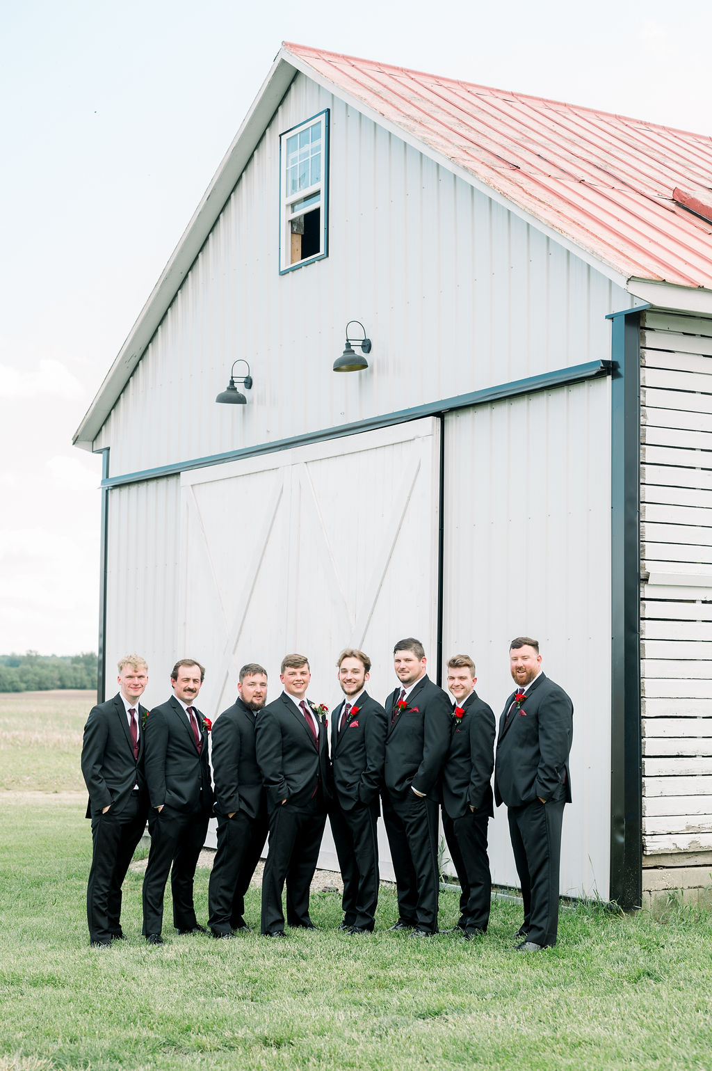 The groom and his groomsmen in suits outside the corn crib at Wren Farm
