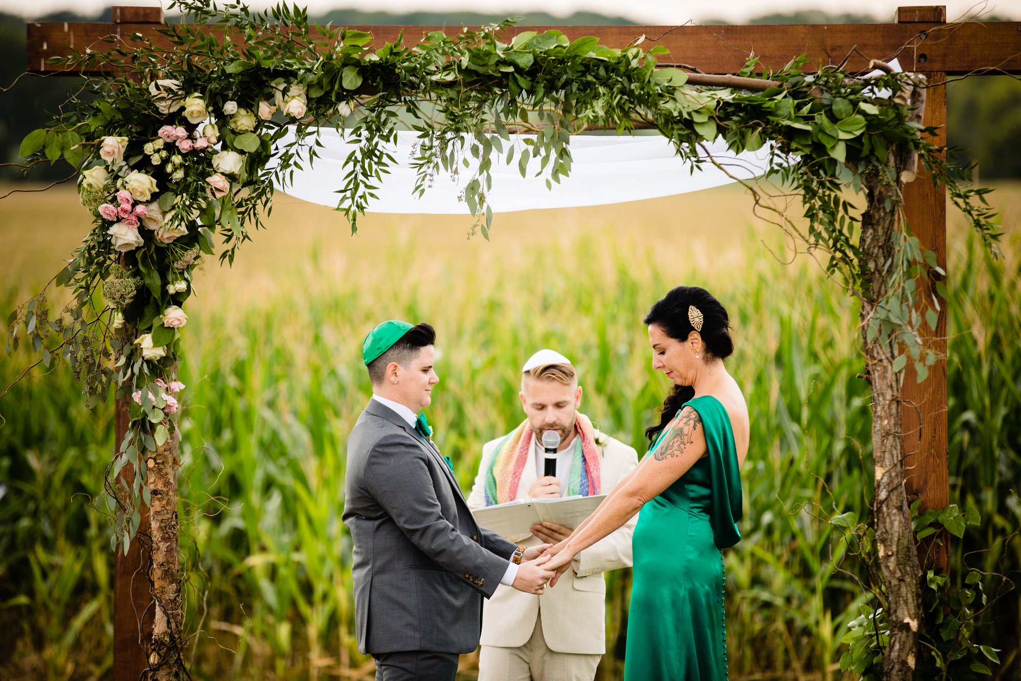 Two partners hold hands beneath the ceremony arch.