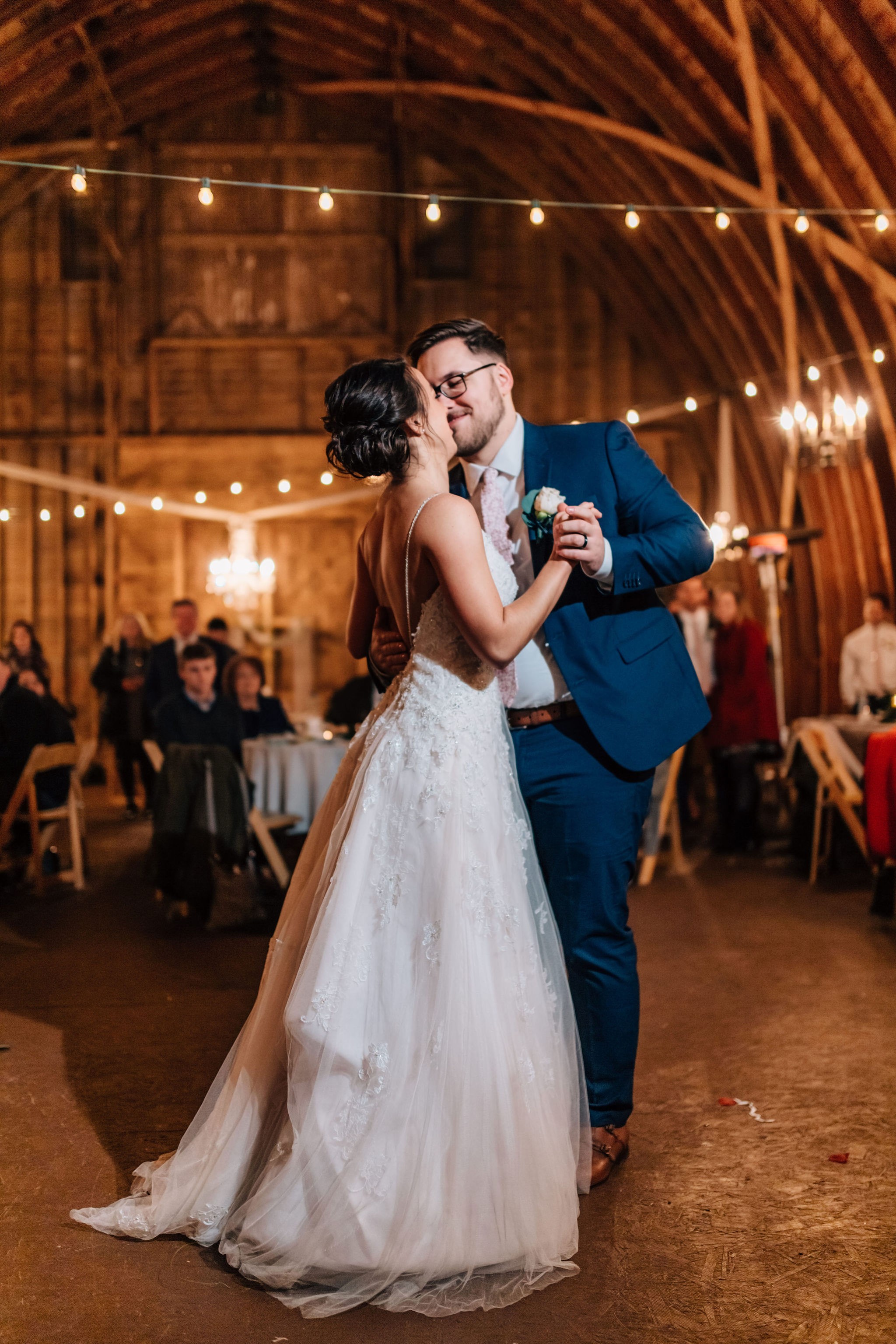 A couple dancing together under the barn lights.