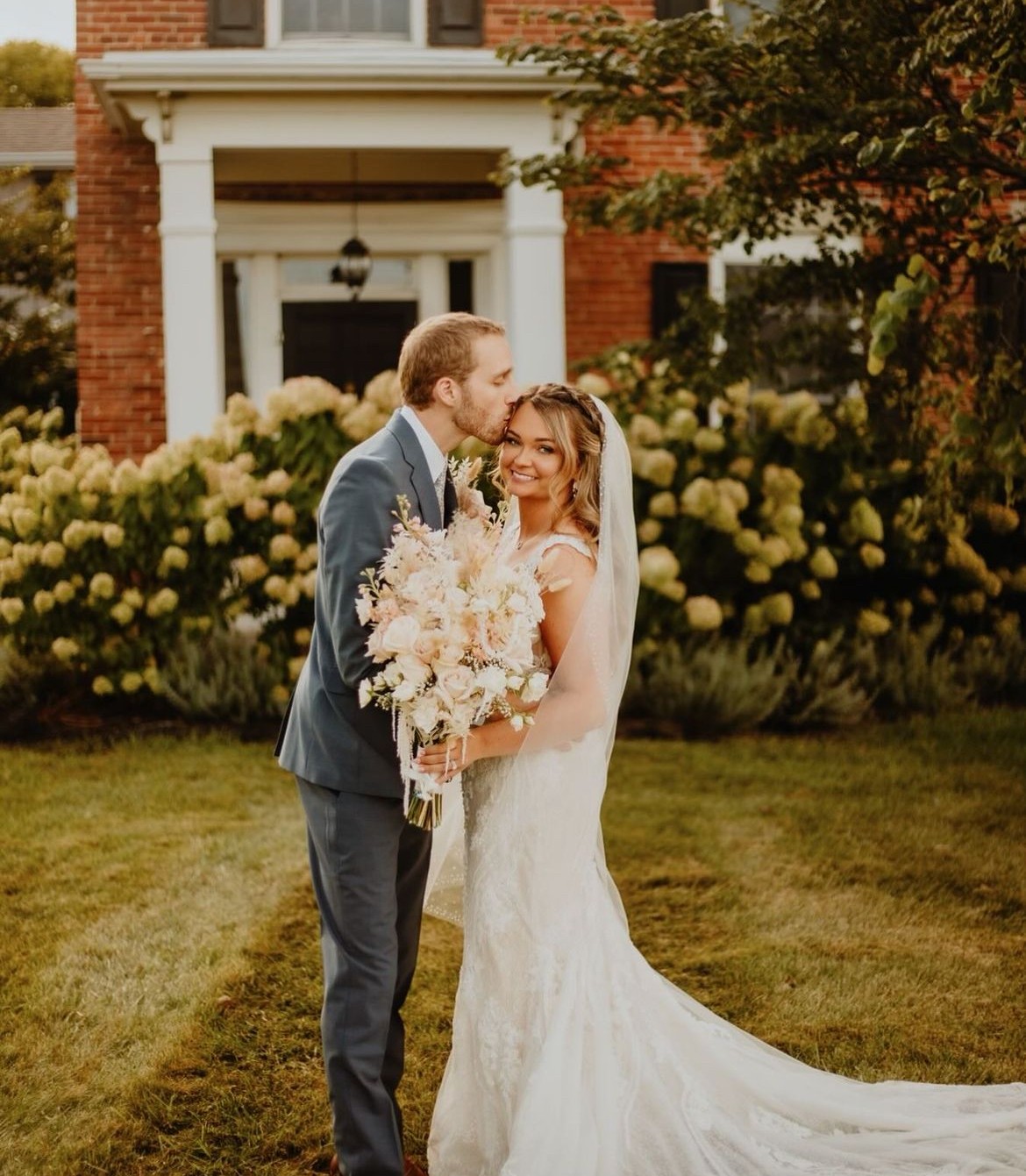 A couple beside the farmhouse hydrangeas in the late afternoon.