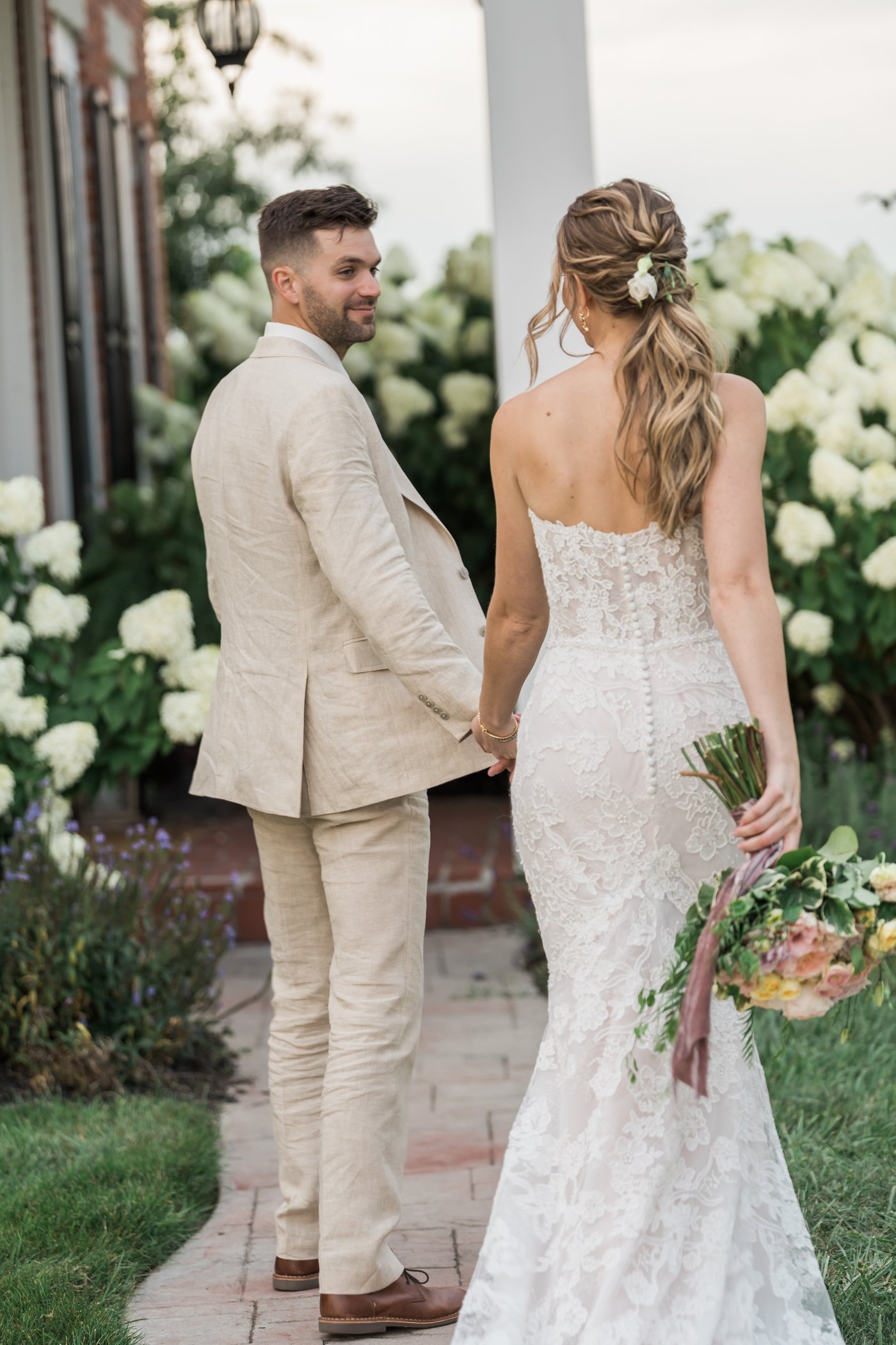 A couple together in front of the white hydrangeas.