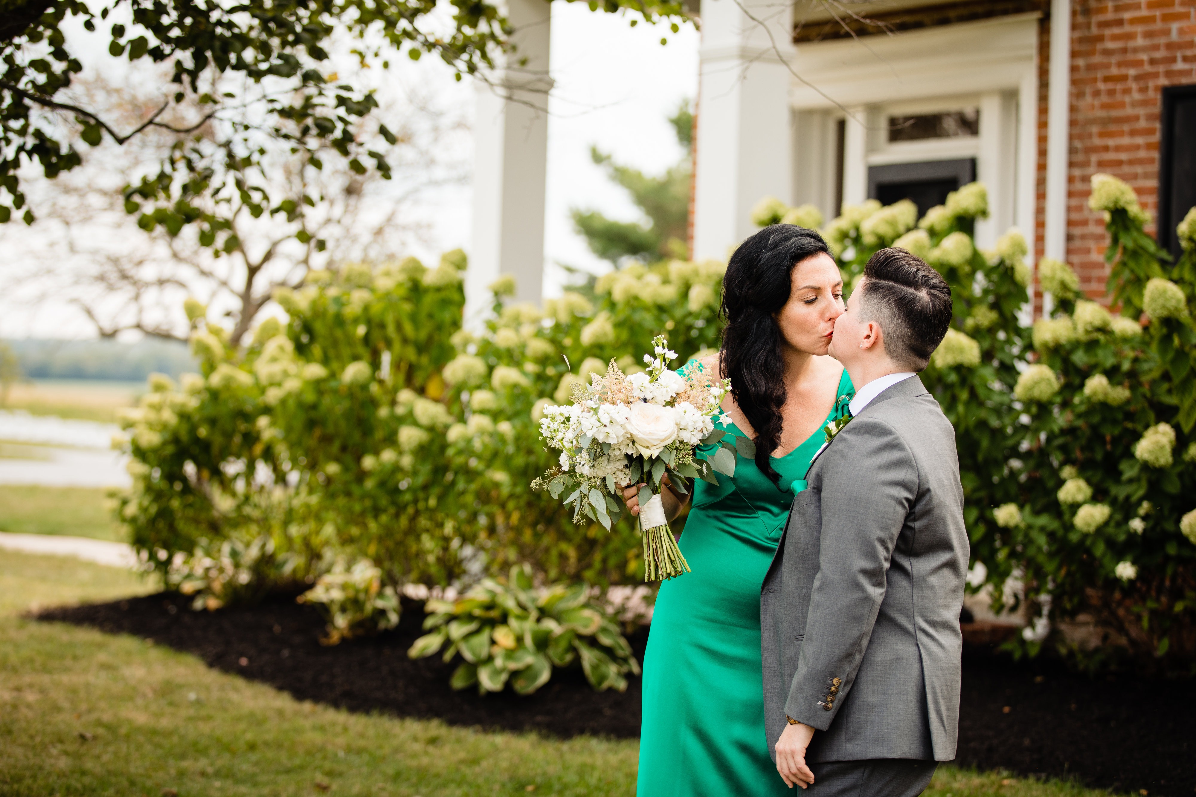 A couple kissing beside the farmhouse hydrangeas.