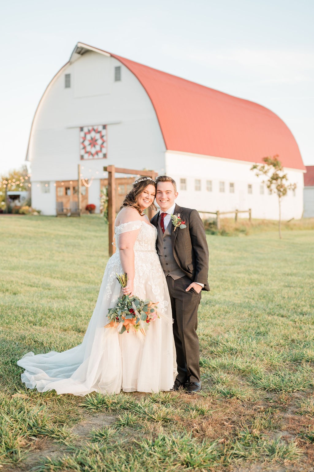 A couple in front of the white barn and its painted quilt block.