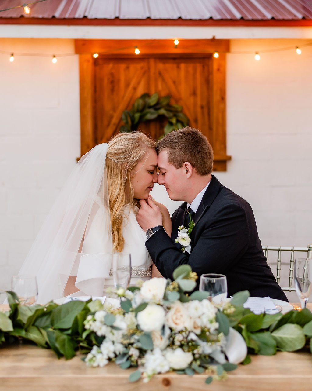 A couple forehead to forehead at the sweetheart table.