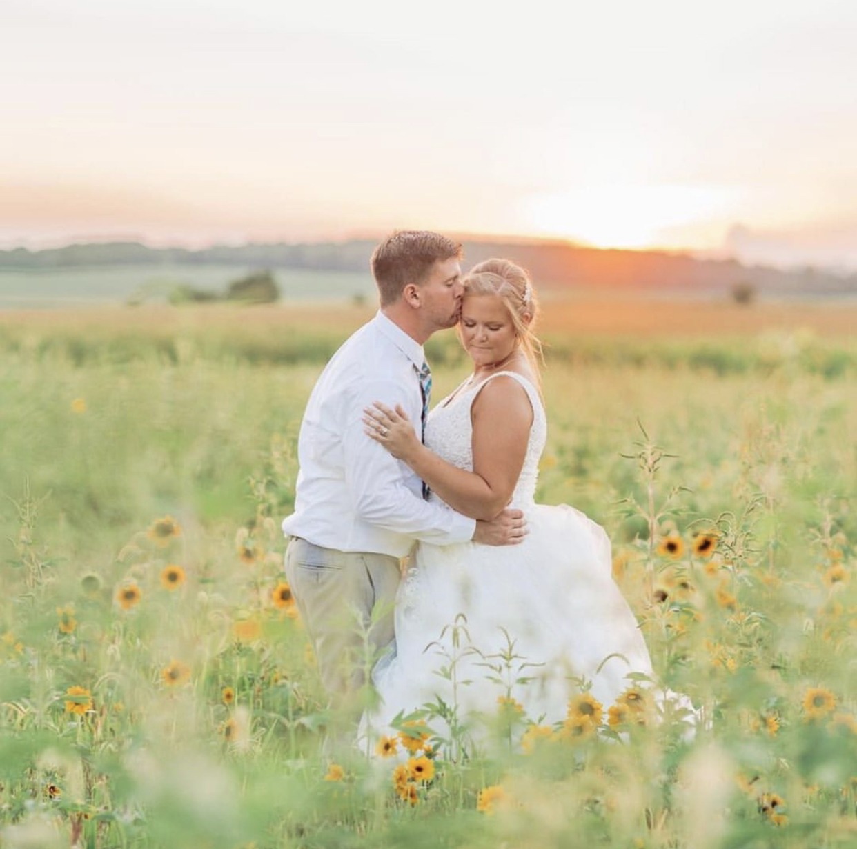 A couple standing together in the sunflower field.