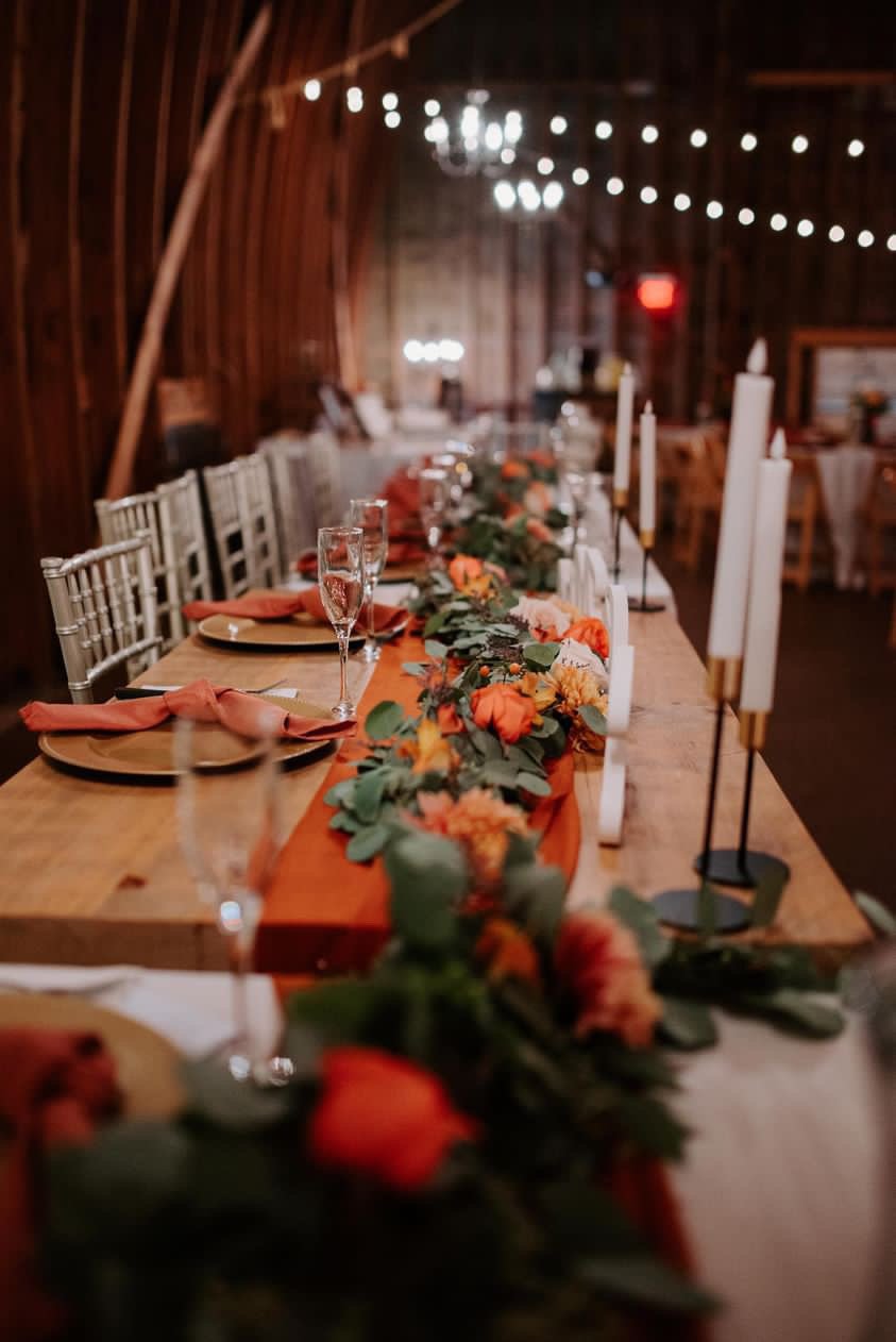 A long reception table dressed for autumn inside the barn.
