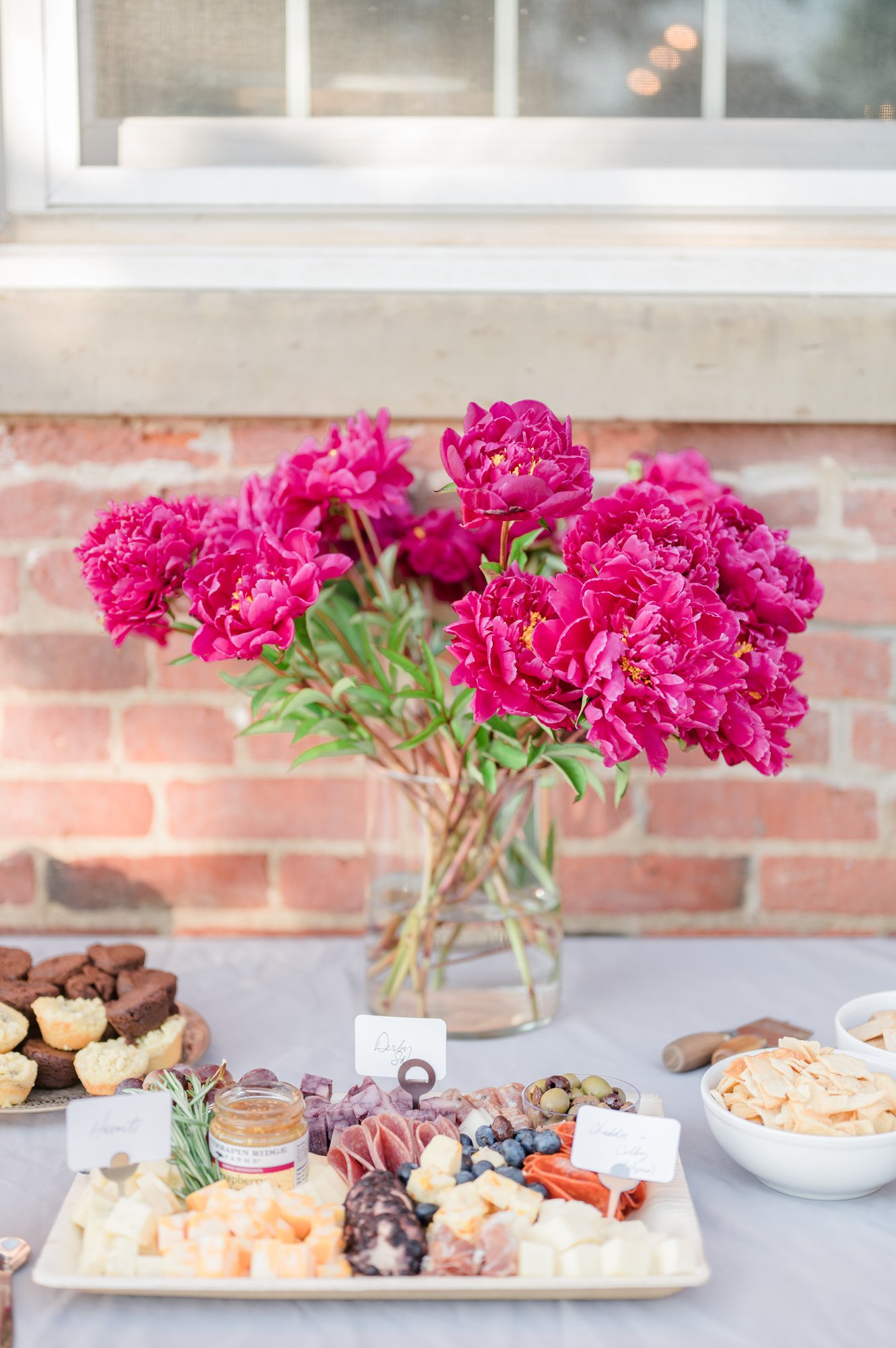 A grazing table of cheese and charcuterie with fresh peonies.