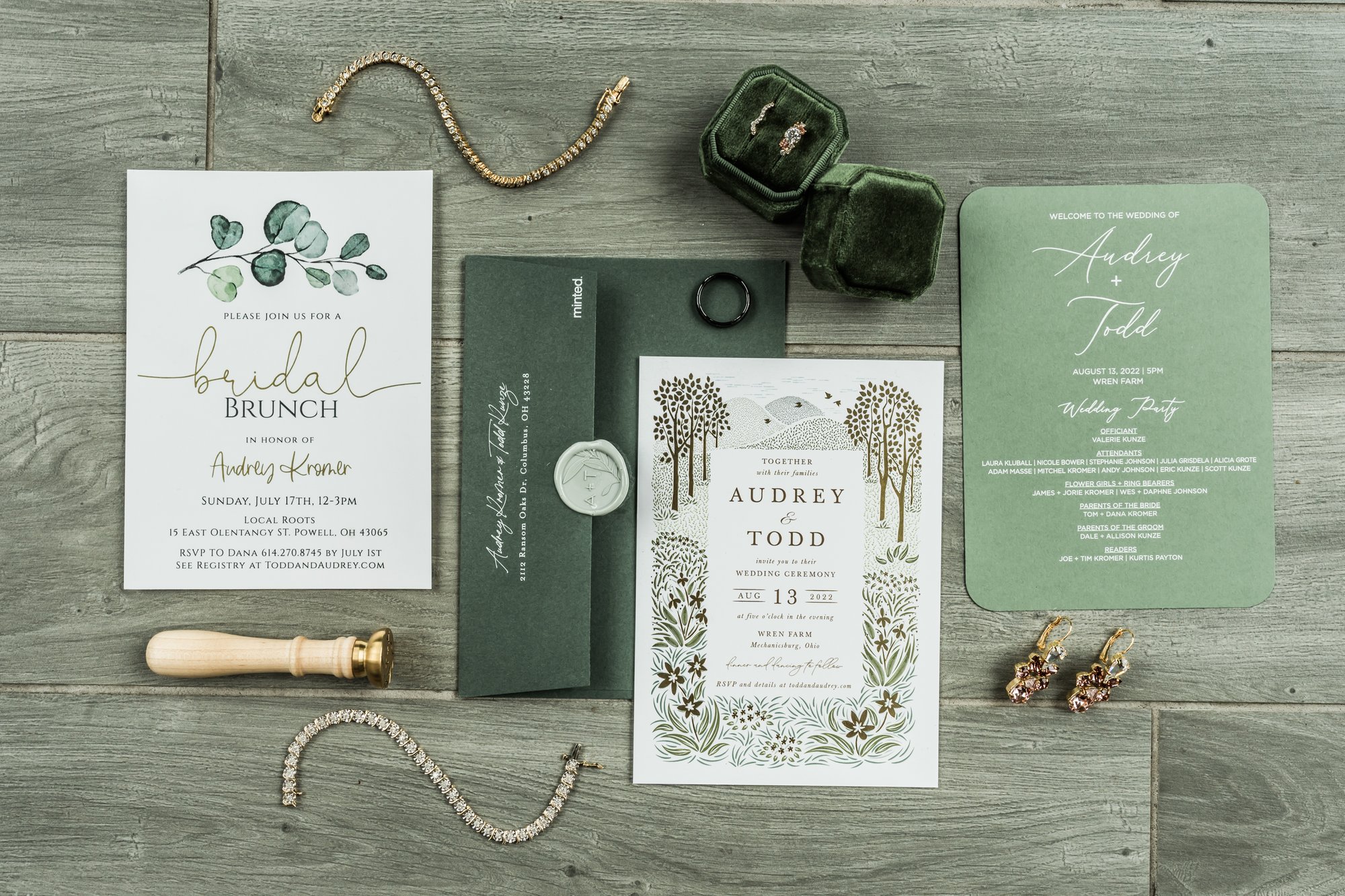 An invitation suite laid out with rings and greenery.