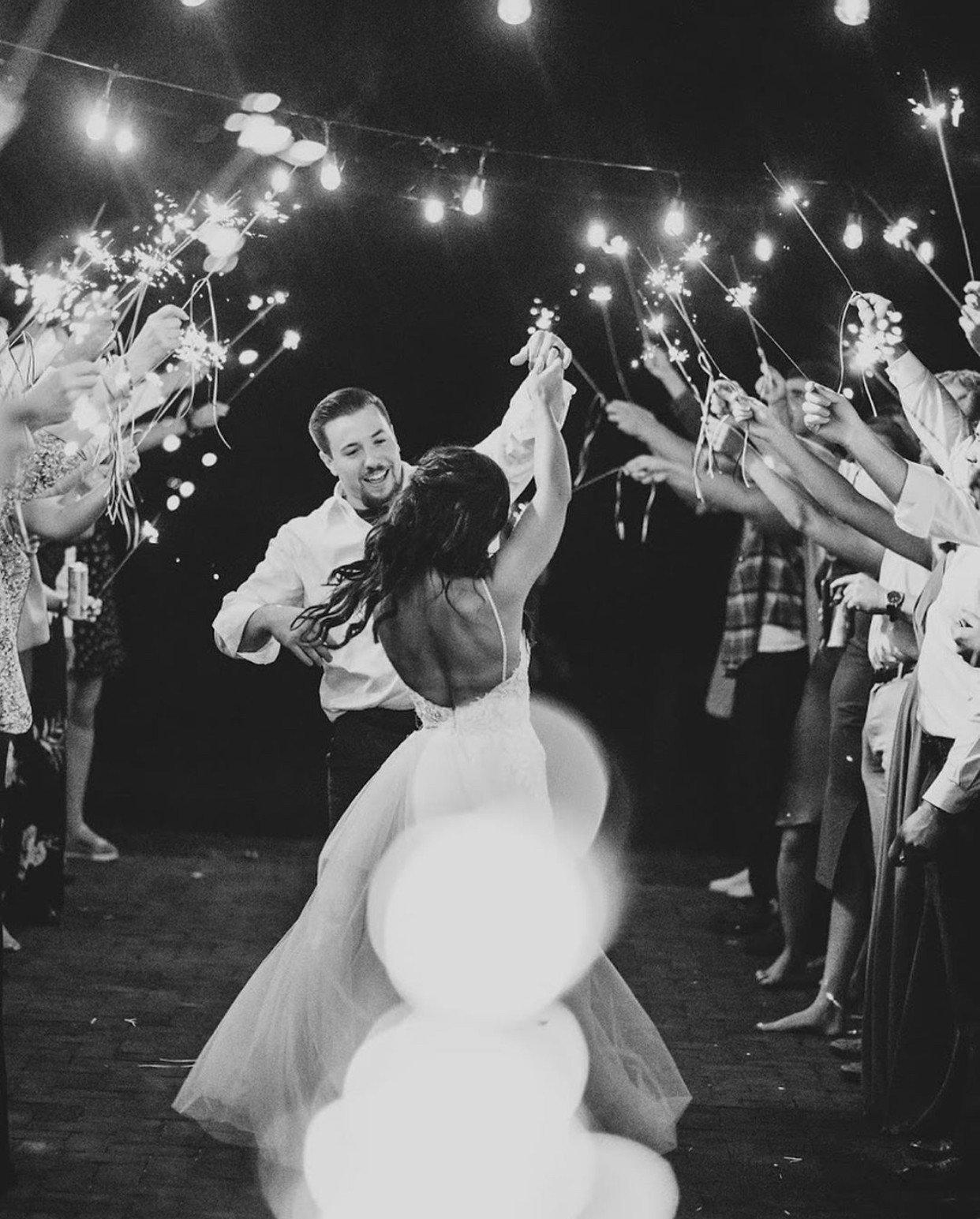 Guests raising sparklers overhead as the couple runs through.