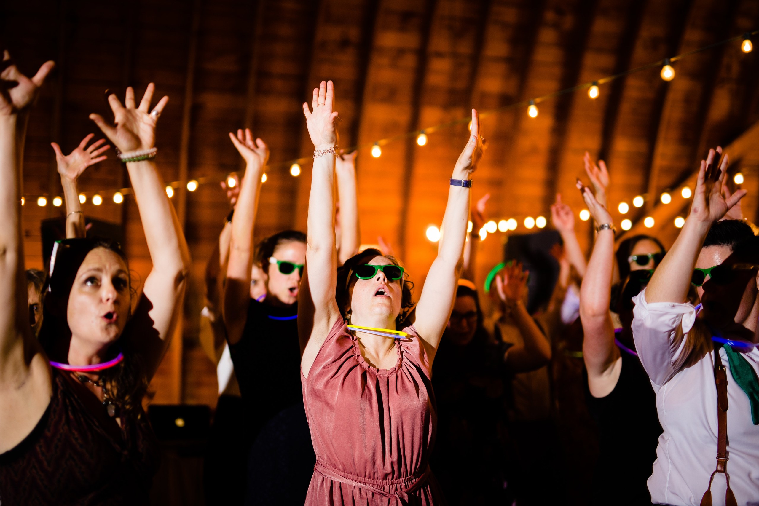 Wedding guests dance together inside the barn late at night.